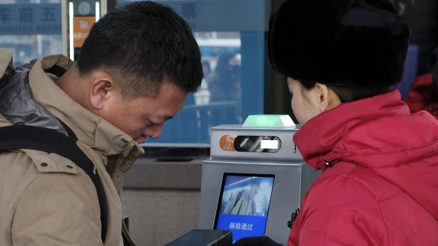 A passenger at Beijing Railway Station goes through a self-service ticket checking machine by getting his face recognised and ID card scanned. This is then linked to data to see if the person is on a black list.