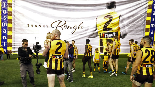 Memorable exit: Jarryd Roughead of the Hawks carries his daughter Pippa through the banner before the game against Gold Coast.