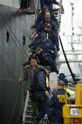 Police escort one of the crew off the Pong Su.
