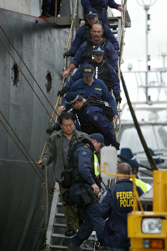 Police escort one of the crew off the Pong Su.