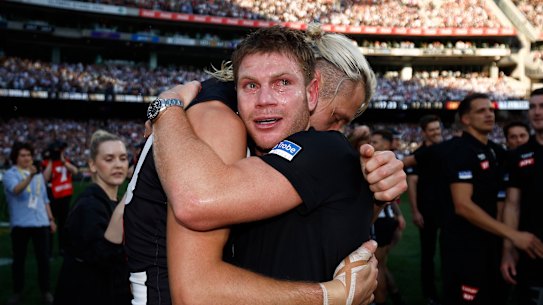 Taylor Adams hugs captain Darcy Moore moments after Collingwood’s premiership win.