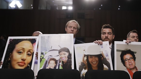 Family members of crash victims holding up photographs of their loved ones at a US Senate hearing last year.