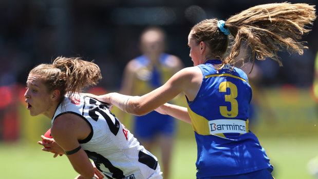 Mikala Cann of the Magpies looks to break from a tackle by Charlotte Thomas.