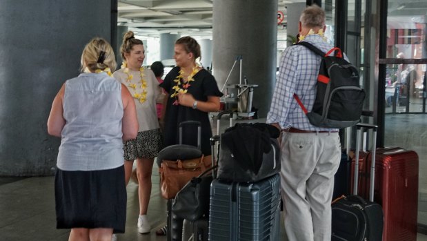 Tourists, freshly presented with frangipani necklaces by one of the women employed solely to do so, arrive at Bali international airport.