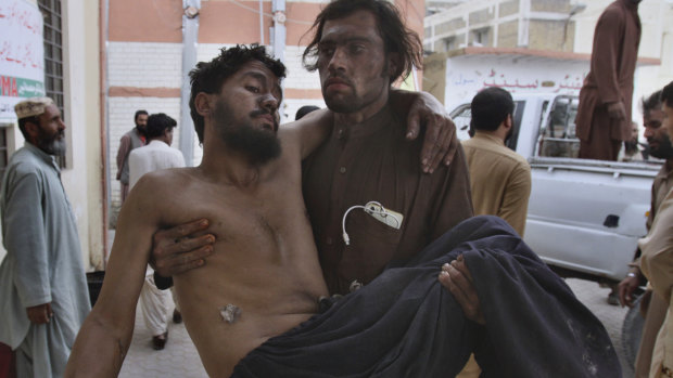 A Pakistani mine worker carries an injured colleague upon arrival at a hospital in Quetta, Pakistan.