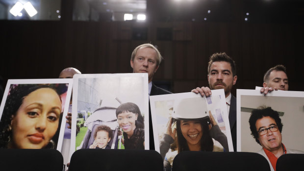 Family members of crash victims holding up photographs of their loved ones at a US Senate hearing last year.