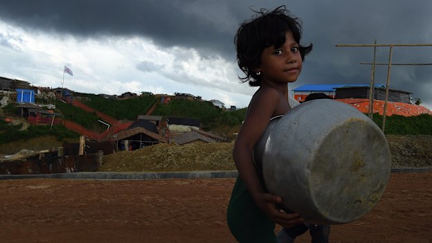 Storm clouds hang overhead as a Rohingya child carries a pot in Kutupalong camp.