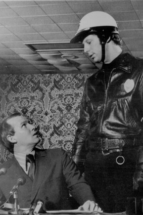 Comedian Tommy Smother looked up at Bob Einstein playing 'Officer Judy' at a press conference for Return of the Smothers Brothers in 1970.