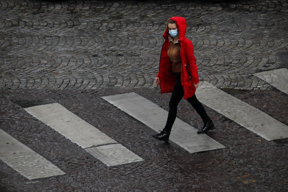 A woman crosses a quiet Paris street on Tuesday. France is under an extended stay-at-home order until May 11.