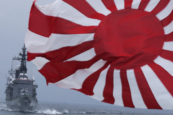 The Japanese escort ship Kurama, left, navigates behind destroyer Yudachi, carrying a rising sun flag - the kyokujitsuki -, during a fleet review off Sagami Bay, south of Tokyo, in 2012.