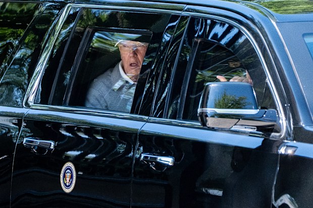 President Donald Trump looks out the window of his limousine as he departs the White House.