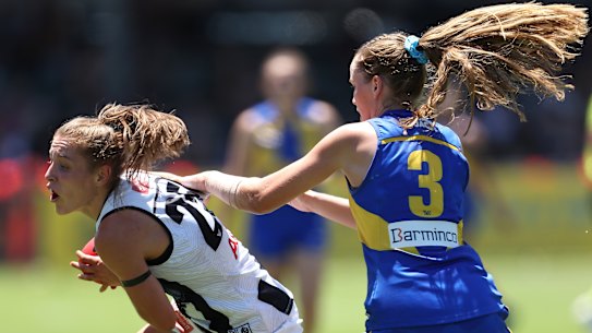 Mikala Cann of the Magpies looks to break from a tackle by Charlotte Thomas.