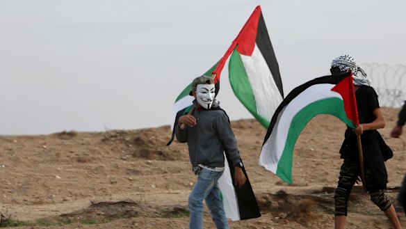 Protesters wave their national flags near the fence of the Gaza Strip border with Israel during a protest east of Gaza City, on Friday.