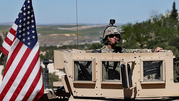 An American soldier sits on his armoured vehicle on a road in Manbij, north Syria, earlier this year.