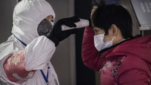 A health worker checks the temperature of a woman entering a subway station in Beijing.