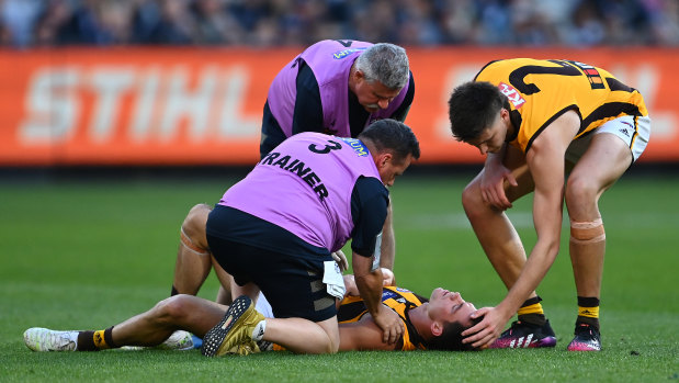 Jaeger O’Meara of the Hawks is attended to by trainers after a collision with Lachie Plowman.
