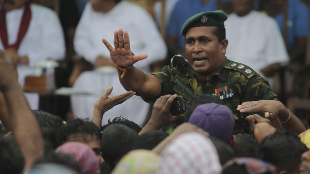 A Sri Lankan police officer tries to control supporters of Sri Lankan President Maithripala Sirisena and his newly appointed Prime Minister Mahinda Rajapaksa during a rally held in Colombo.