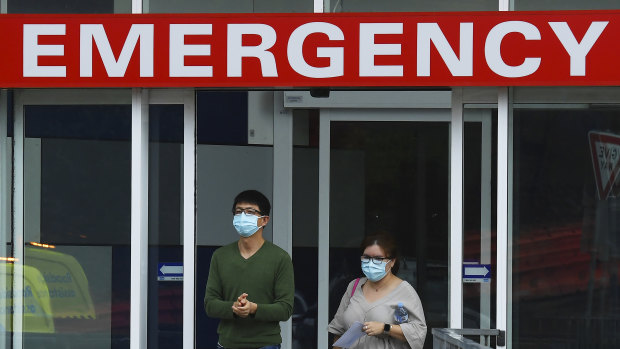 Two people wearing face masks walk out of the emergency entrance at Westmead Hospital in Sydney. 