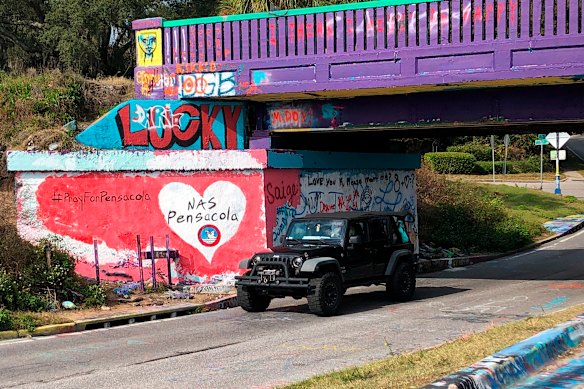 A vehicle drives by a tribute to victims of the shooting at a Naval air station in Pensacola.