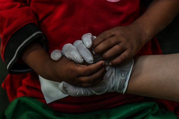 A child holds the hands of a health worker during treatment at an army rescue camp in Trishuli Batar, Nepal.