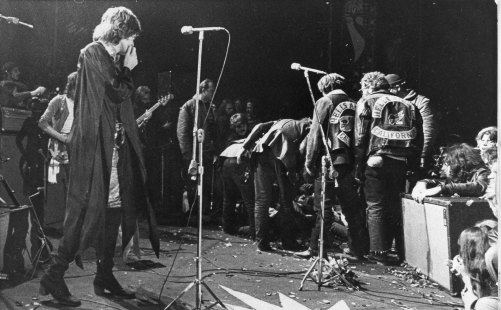 Mick Jagger looks on as Hells Angels bikers drag a person onstage at the Altamont rock festival in December, 1969.