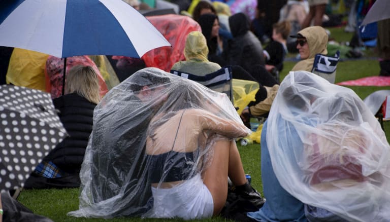Music fans seek shelter from the rain at the Lost Picnic festival in the Domain.