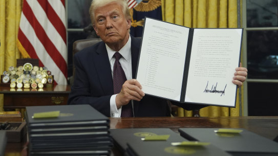 President Trump holds up an executive order commuting sentences for people convicted over the January 6, 2021, riots on Capitol Hill.