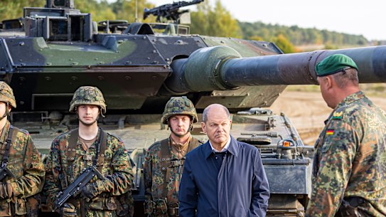 German Chancellor Olaf Scholz, in blue, talks to German soldiers by a Leopard 2 main battle tank during an exercise in Ostenholz, Germany, in October.