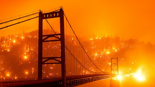 In this image taken with a slow shutter speed, embers light up a hillside behind the Bidwell Bar Bridge as the Bear Fire burns in Oroville, Calif., on Wednesday, Sept. 9, 2020. (AP Photo/Noah Berger)