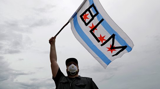 A protester waves a city of Chicago flag emblazoned with the acronym BLM for Black Lives Matter, outside the Batavia, Ill., City Hall during a protest over the death of George Floyd, on Wednesday, June 3, 2020, Floyd, an African American, died on May 25 after a white Minneapolis police officer pressed a knee into his neck for several minutes even after he stopped moving and pleading for air. (AP Photo/Nam Y. Huh)