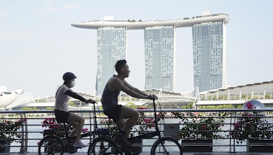 Cyclists ride past the Marina Bay Sands Hotel in Singapore, where curbs have been tightened this week.