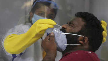 A health care worker takes a nasal swab sample to test for COVID-19 in Hyderabad, India.