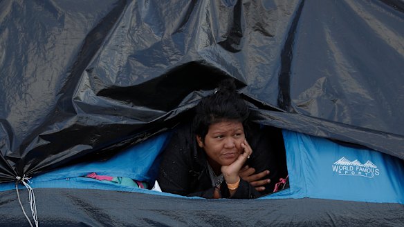 A woman rests inside a tent on the street near a sports complex shelter as authorities tried to persuade migrants to move to a new, more distant shelter, in Tijuana, Mexico, on Saturday.