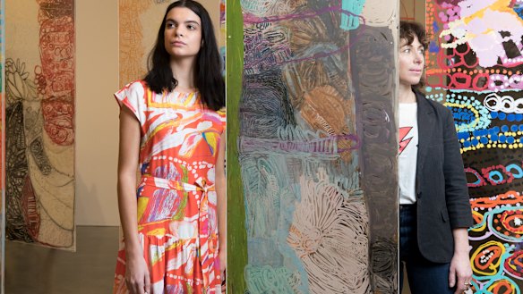 Lisa Gorman with model Domanique 
Hutchins, wearing a dress from the Mangkaja collection in front of Mangkaja Arts perspex installation, artworks by Daisy Japulija, Lisa Uhl, Nada Rawlins and Sonia Kurarra  at The National 2019, Museum of Contemporary Art.      