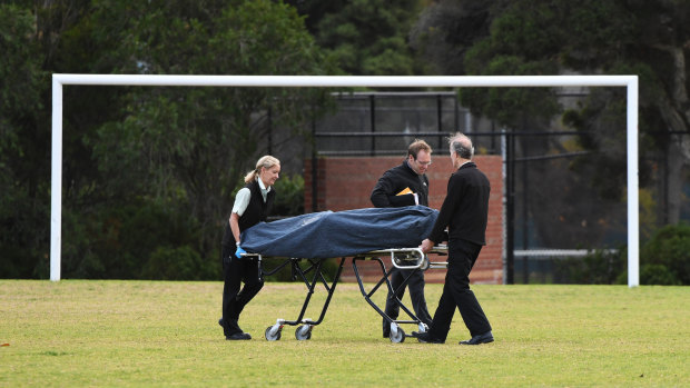 The woman's body is removed from the centre of a soccer pitch in Princes Park, Carlton North, on Wednesday.
