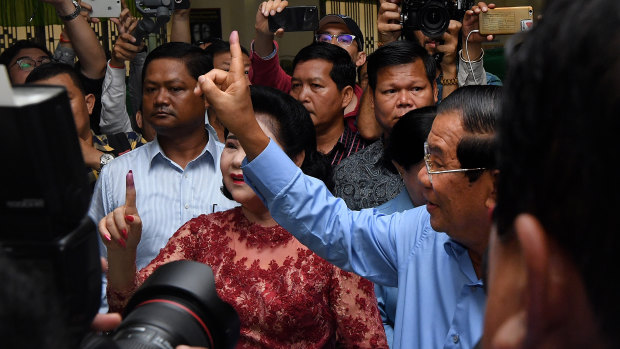 Hun Sen (right) raises his finger indicating he has voted in the Cambodian general election.