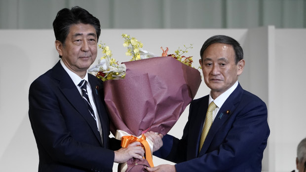 Yoshihide Suga (R) presents flowers to his predecessor Shinzo Abe after Suga was elected as new head of Japan’s ruling party in September.