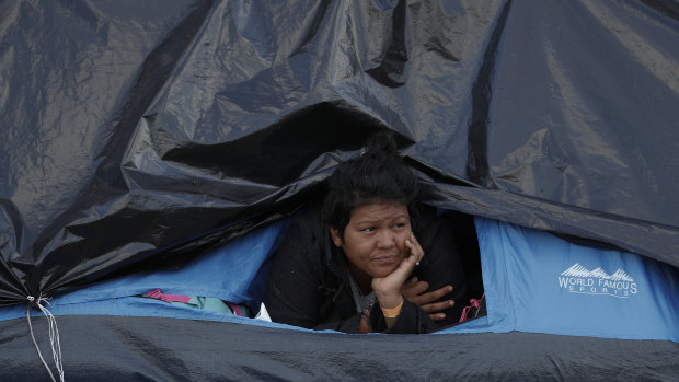 A woman rests inside a tent on the street near a sports complex shelter as authorities tried to persuade migrants to move to a new, more distant shelter, in Tijuana, Mexico, on Saturday.