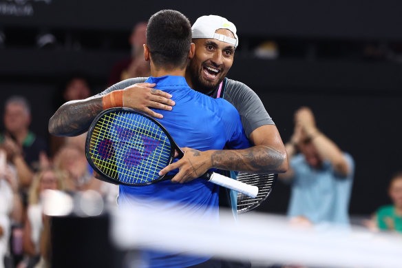 Nick Kyrgios and Novak Djokovic embrace after winning their first doubles match.
