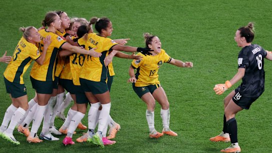 Mackenzie Arnold (right) embraces her Matildas teammates after Australia won the penalty shootout against France in the World Cup quarter-final.