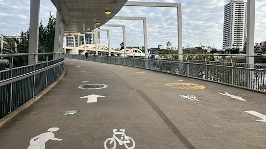 Signs indicating the previous 10km/h speed limit on the Kurilpa Bridge have been painted over on the concrete, but the black markings have worn down.