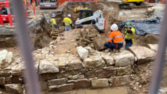 A bulldozer breaking up and removing the significant archaeological remains under Adelaide Street.