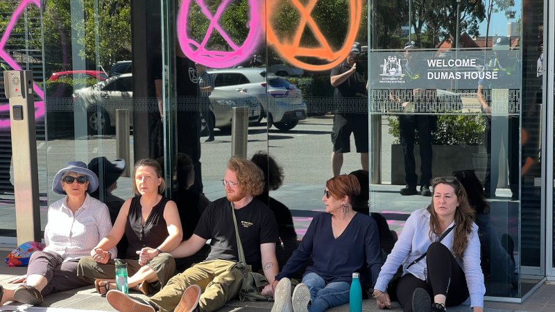Six charged after activists glue hands to ground at premier’s Perth office