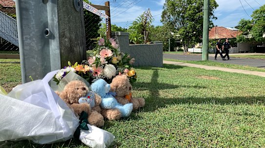 Floral tributes and teddy bears placed near the scene.