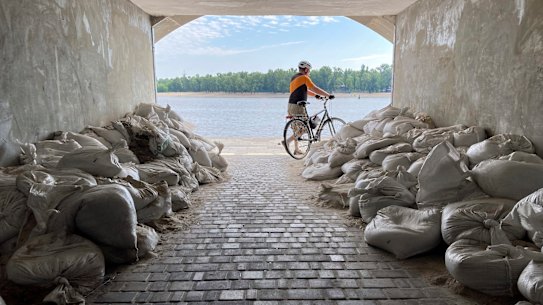 A Sunday morning cyclist emerges from a sandbagged tunnel next to the Dnipro River in Kyiv, Ukraine, earlier this month. Britain says Russia has troops stationed near the waterway.