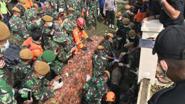 Rescue workers pull a body out of a small cellar, underneath the Tanjung Lesung beach resort’s pool.