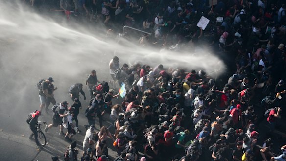 Police fight protesters with a water cannon in Santiago on Monday.