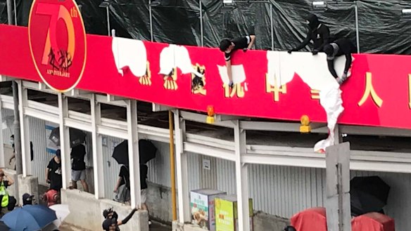 Protesters tear down a newly erected red banner celebrating the 70th anniversary of Communist China.