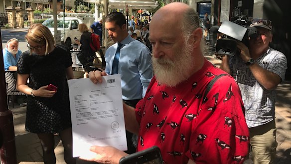 Chris Maltby, treasurer of Local Democracy Matters, holds up orders outside the Land and Environment Court on Tuesday.