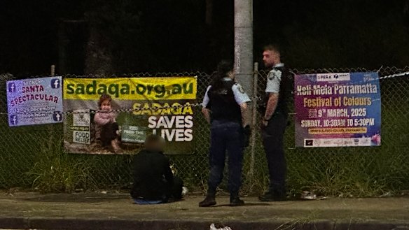 Police guard a man in handcuffs near the scene of Sunday night’s shooting
 